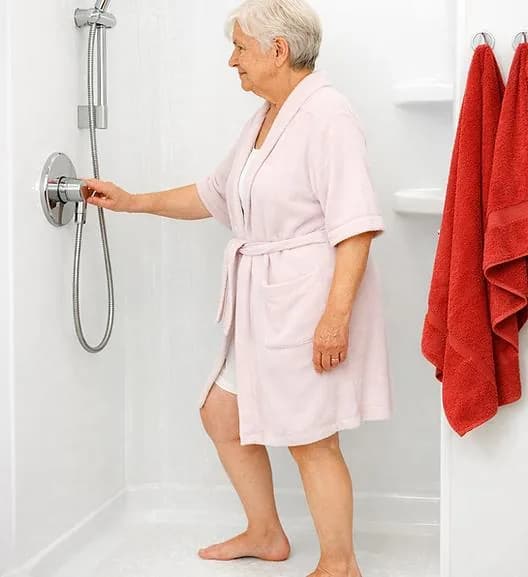 Older woman at a curbless shower using the handheld shower