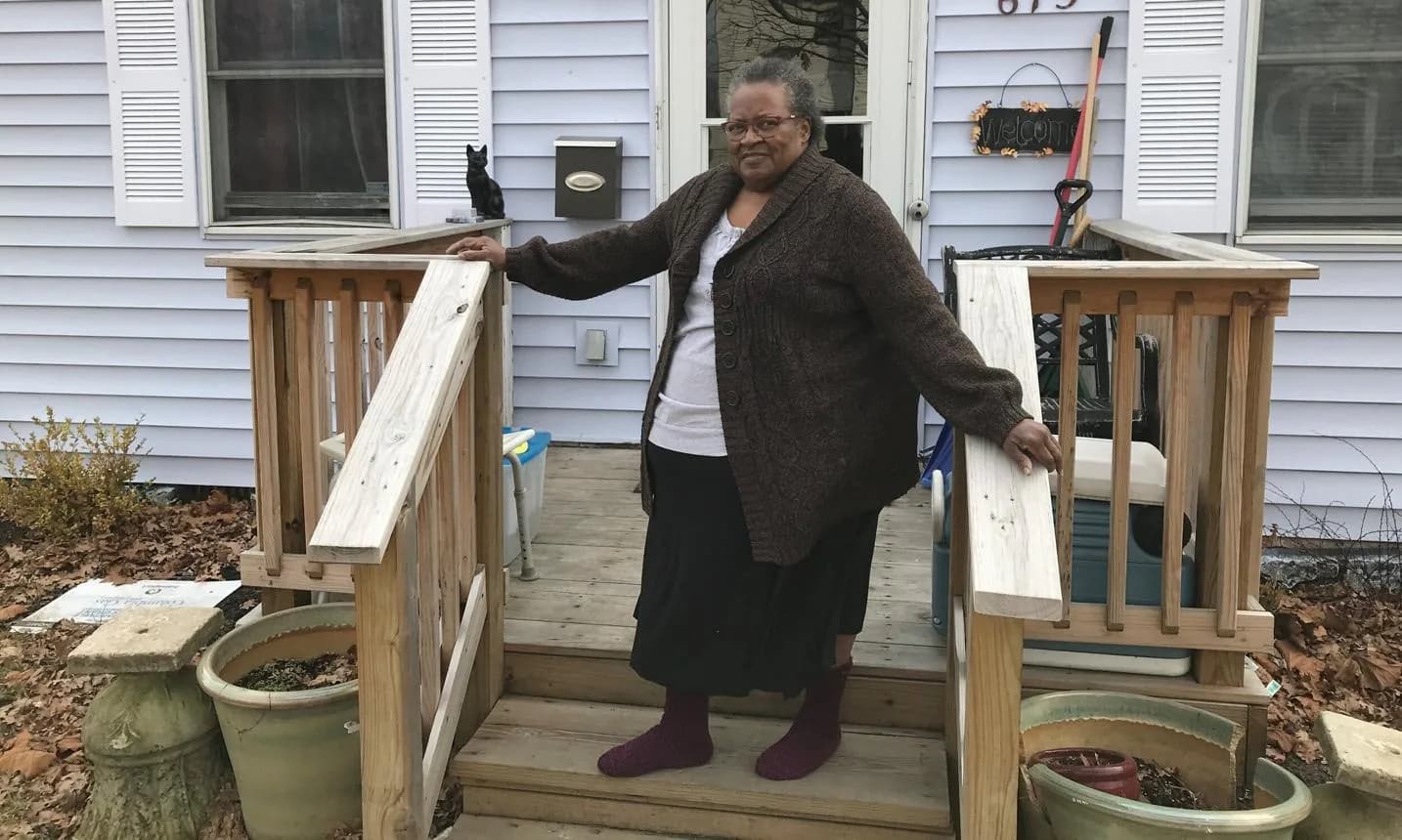 Older woman on wooden entry steps with railings on both sides